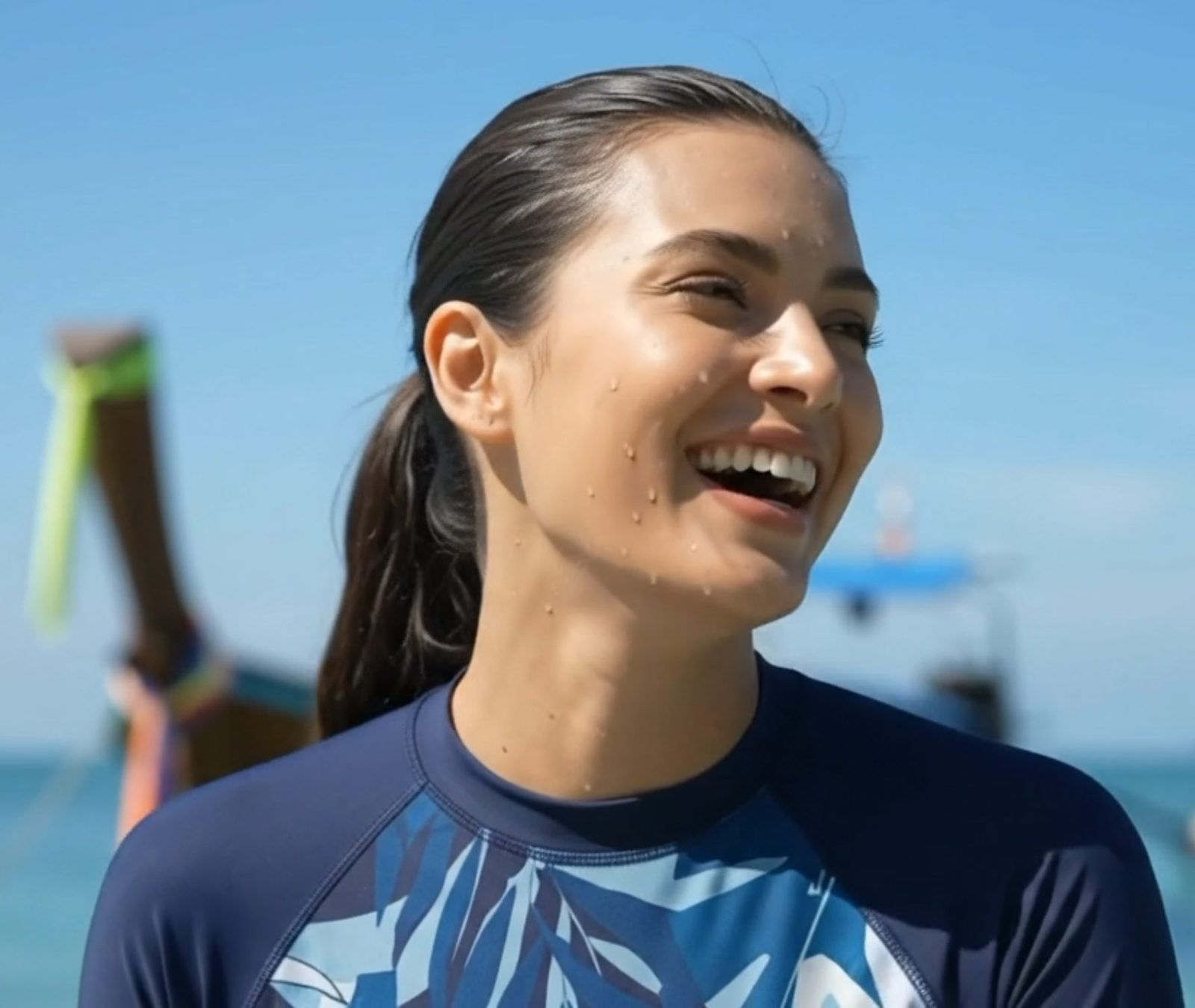 Woman smiling in a custom recycled-fabric rashguard by the sea